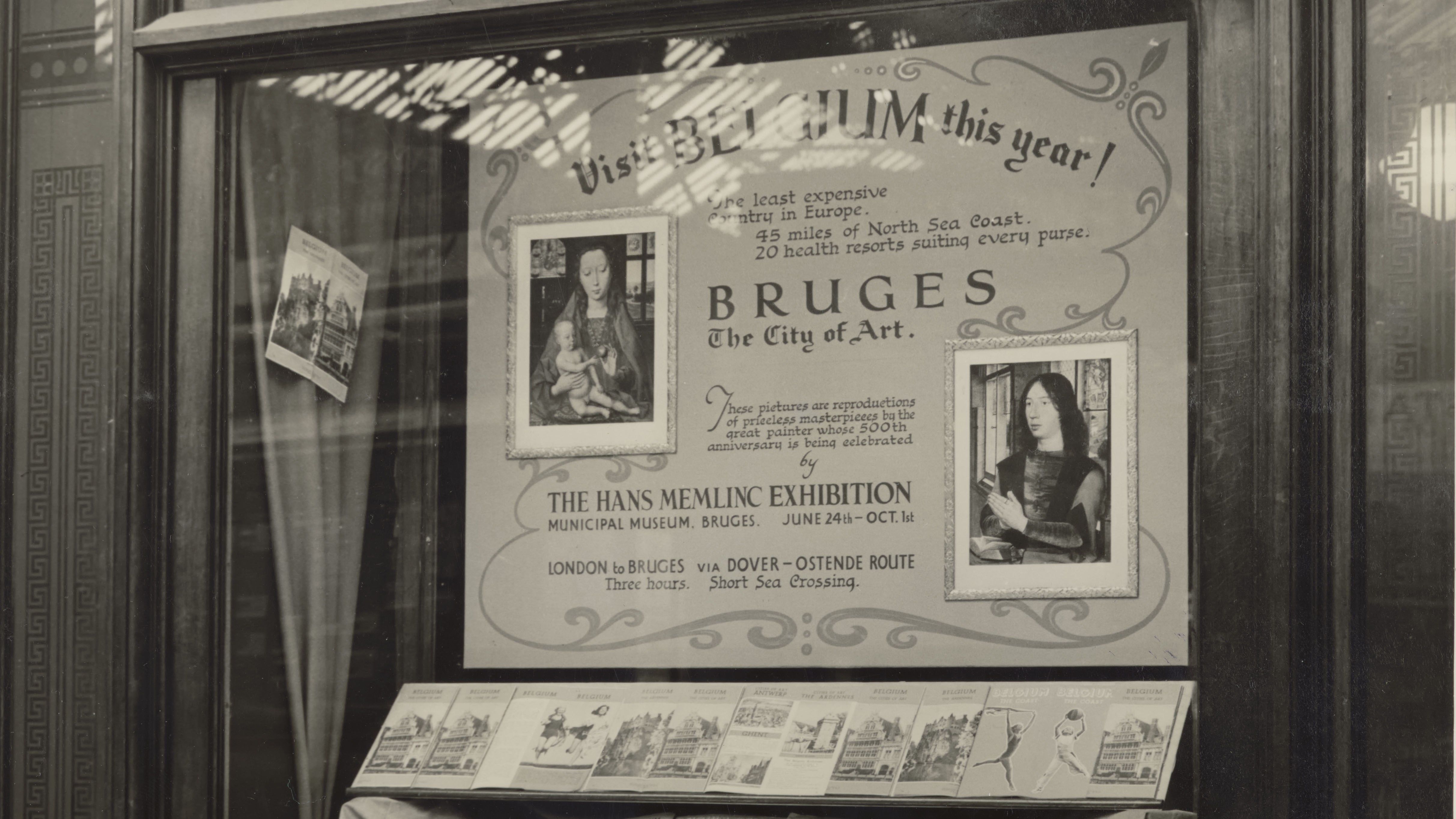 Zwart-witfoto van een vitrine in Victoria Station, Londen uit 1939. Op de foto is een vitrine te zien waarin de Memlingtentoonstelling n.a.v. de 500ste geboortedag van Hans Memling in het Stedelijk Museum - het latere Groeningemuseum - wordt aangekondigd.